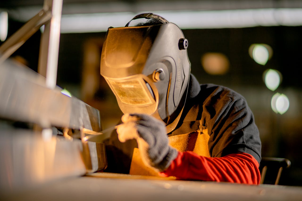 A welder focused on metalwork in an industrial factory, showcasing skill and precision.